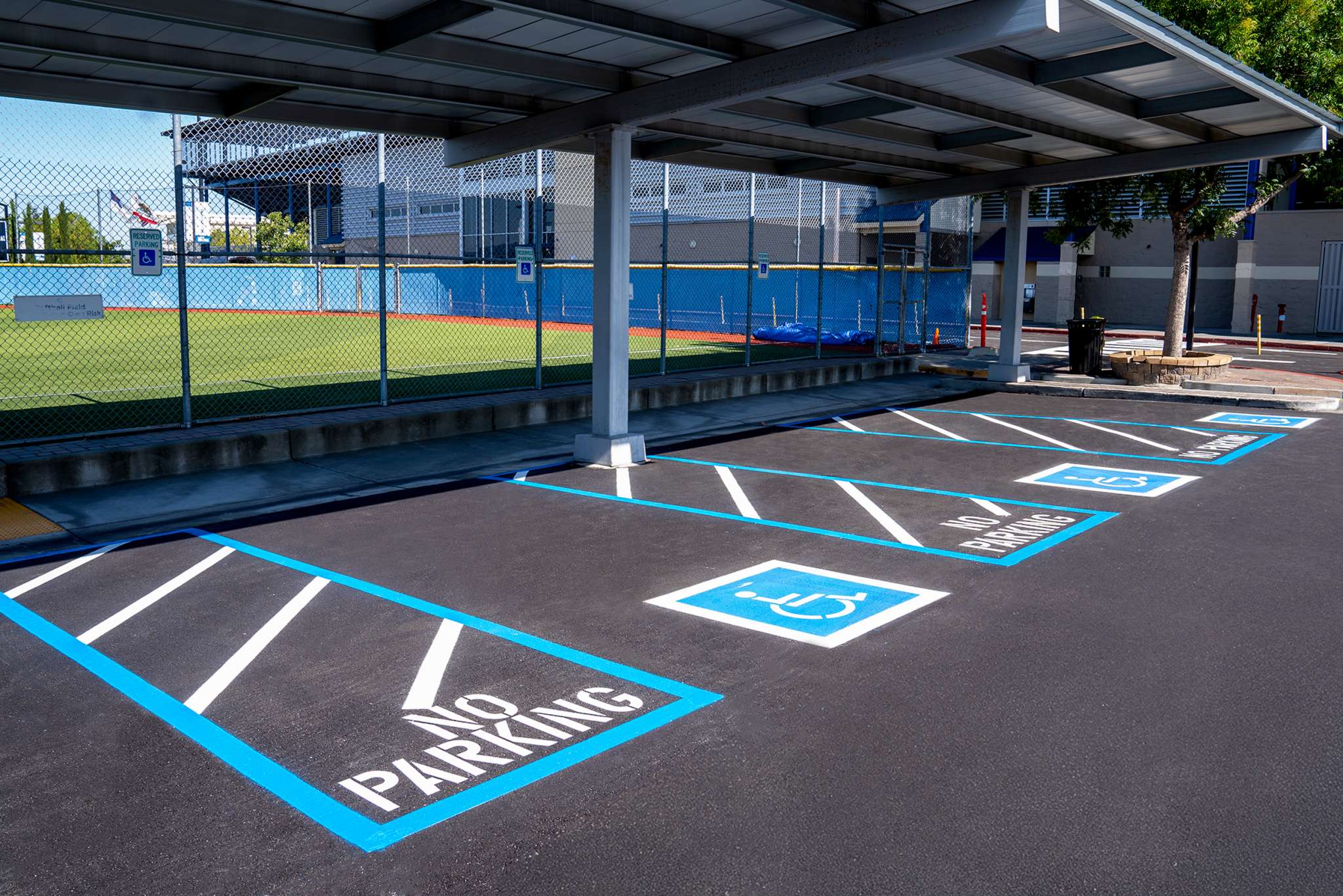 Crisp ADA striping and no-parking zones in a freshly paved lot outside a large building by Pacific Surfacing