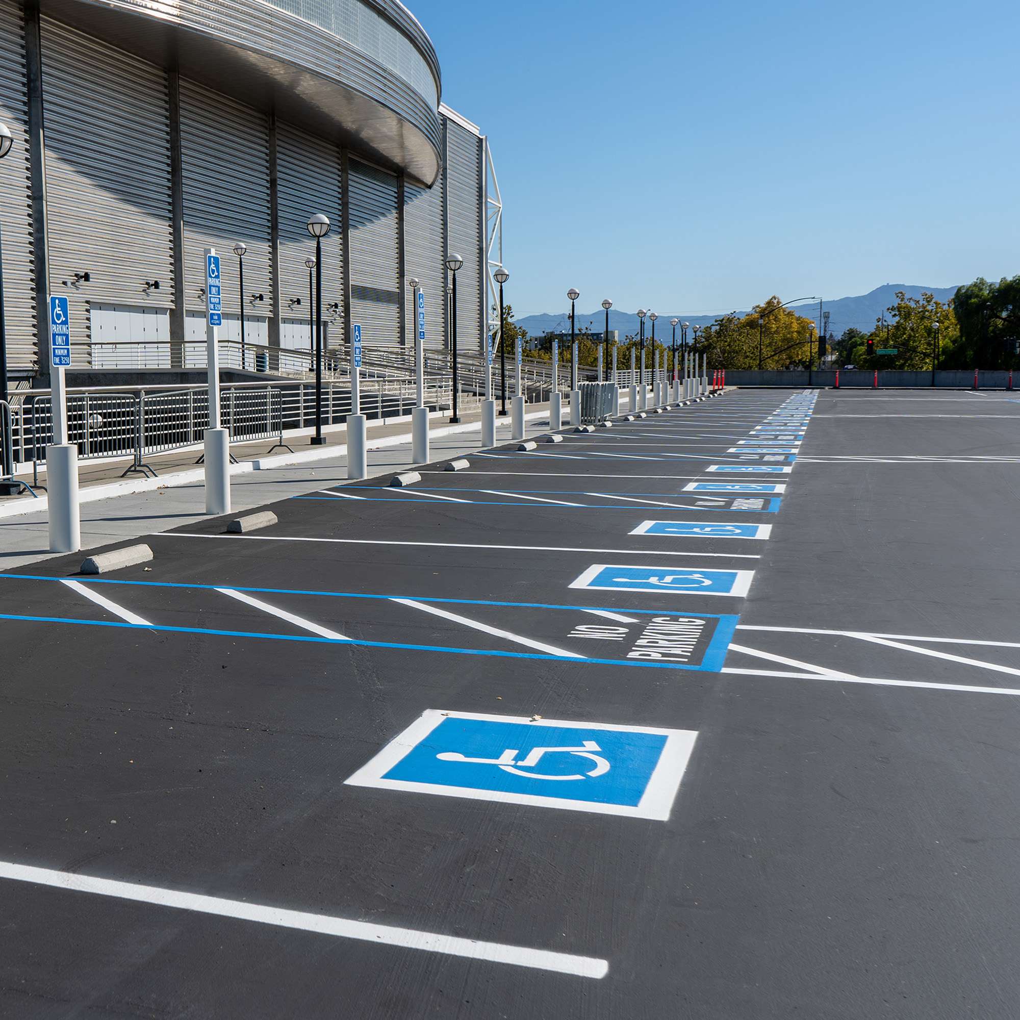 Crisp ADA striping and no-parking zones in a freshly paved lot outside a large building by Pacific Surfacing