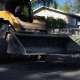A Pacific Surfacing skid-steer spreads loose asphalt on a neighborhood street.