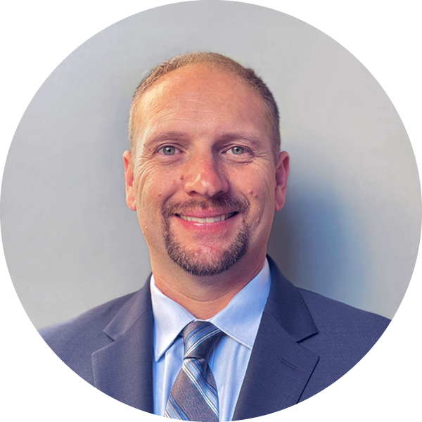 Jeff Tchorzewski, Estimator, smiling in a suit and tie against a gray background.