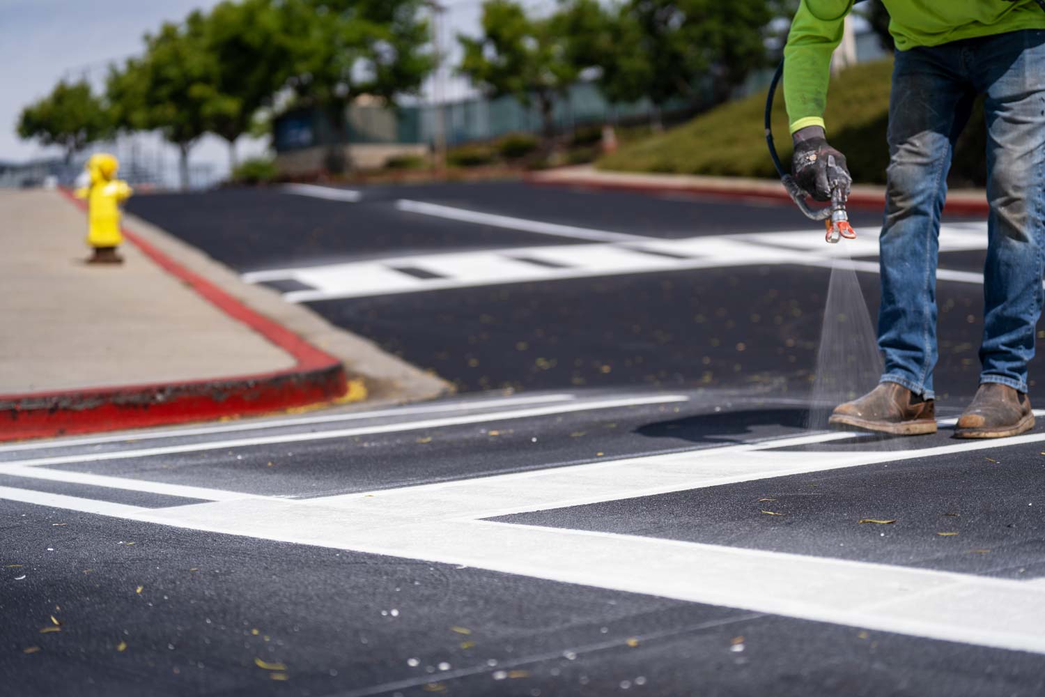Pacific Surfacing crew member applying striping to asphalt