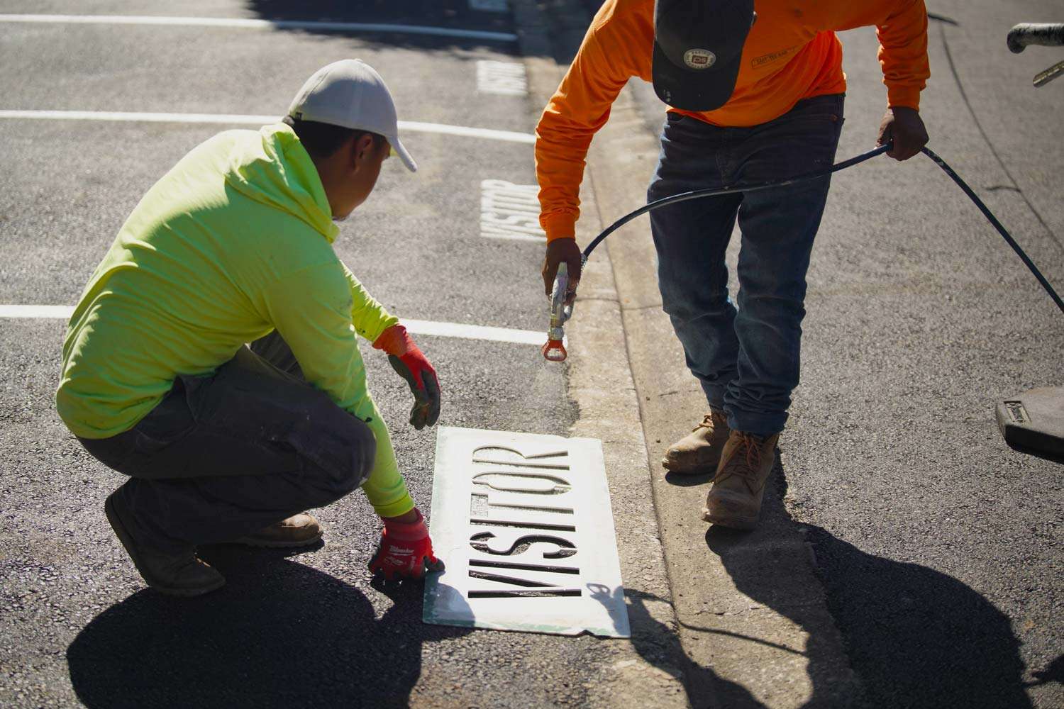 Pacific Surfacing crew members adding visitor parking striping to a parking lot.
