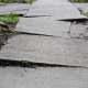Lifted and cracked concrete sidewalk with a significant trip hazard.