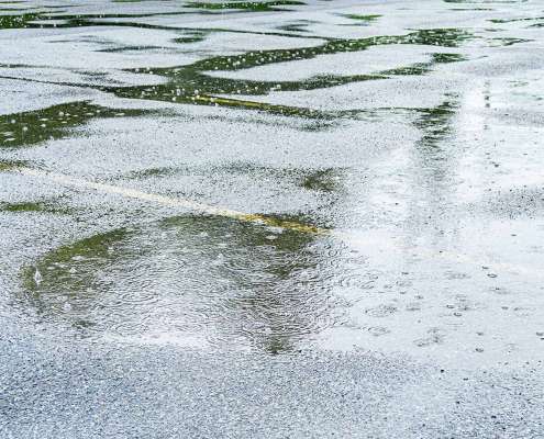 Rain puddles form in a parking lot.