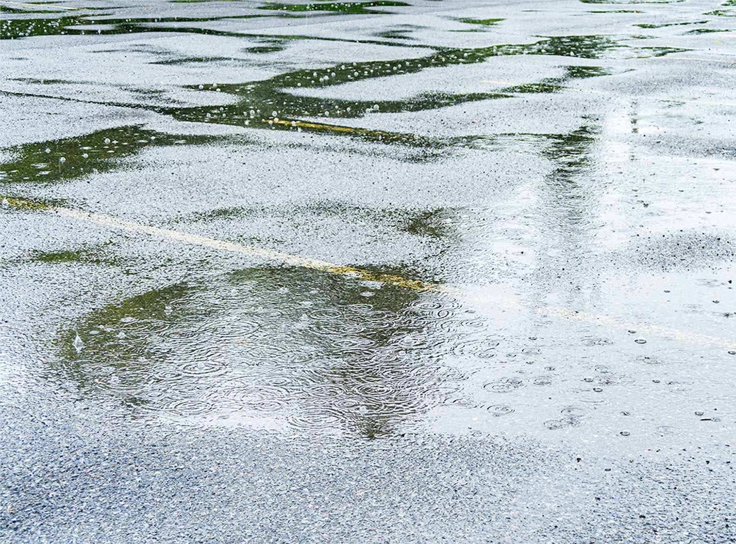 Rain puddles form in a parking lot.